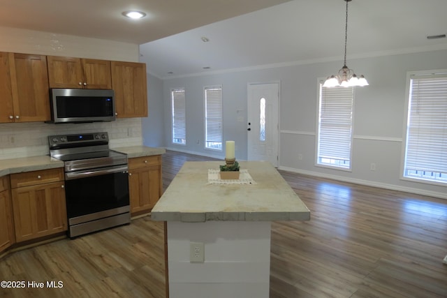 kitchen with decorative backsplash, a kitchen island, ornamental molding, and appliances with stainless steel finishes