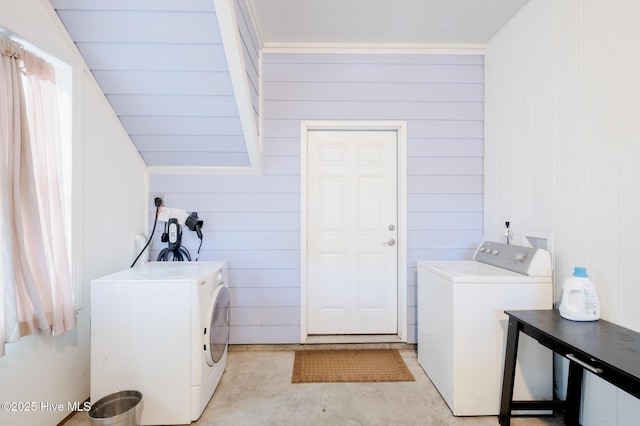 clothes washing area featuring wood walls and washing machine and clothes dryer