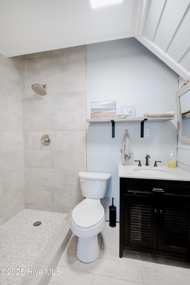 bathroom featuring a tile shower, vanity, and toilet