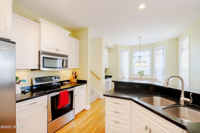 kitchen with sink, stainless steel appliances, light hardwood / wood-style floors, decorative light fixtures, and white cabinets