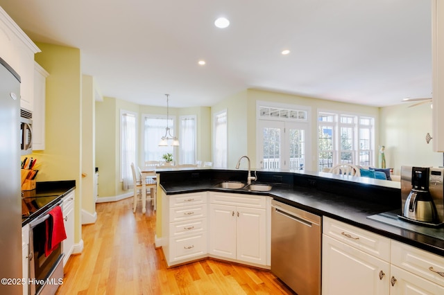 kitchen with sink, hanging light fixtures, light hardwood / wood-style flooring, stainless steel dishwasher, and white cabinets