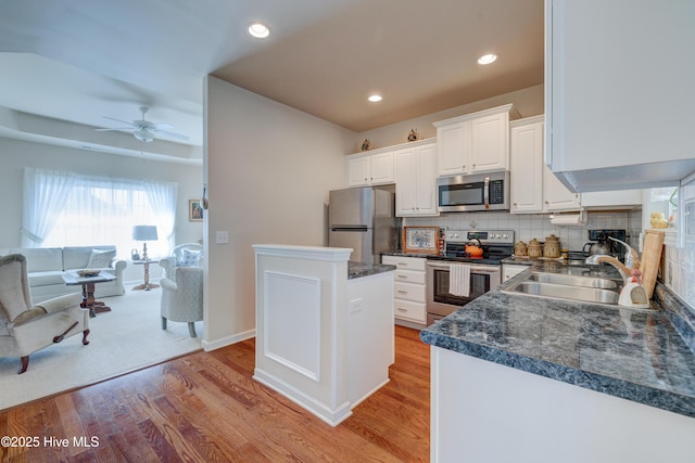 kitchen with white cabinets, sink, decorative backsplash, light wood-type flooring, and stainless steel appliances