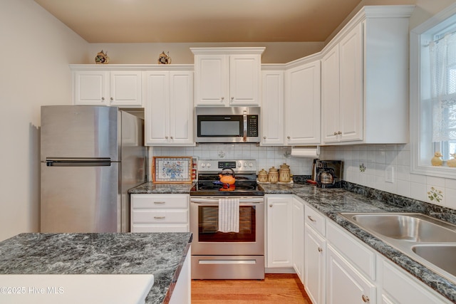 kitchen featuring decorative backsplash, stainless steel appliances, white cabinetry, and sink