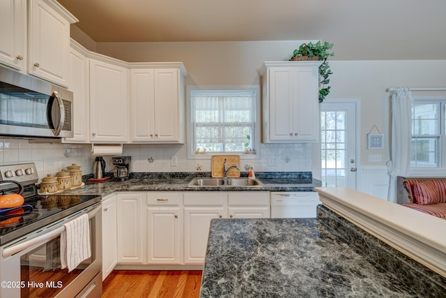 kitchen featuring backsplash, stainless steel appliances, sink, light hardwood / wood-style floors, and white cabinetry