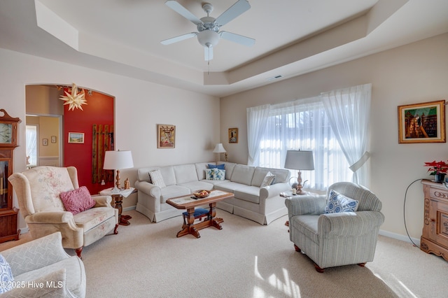 living room with light carpet, a tray ceiling, and ceiling fan