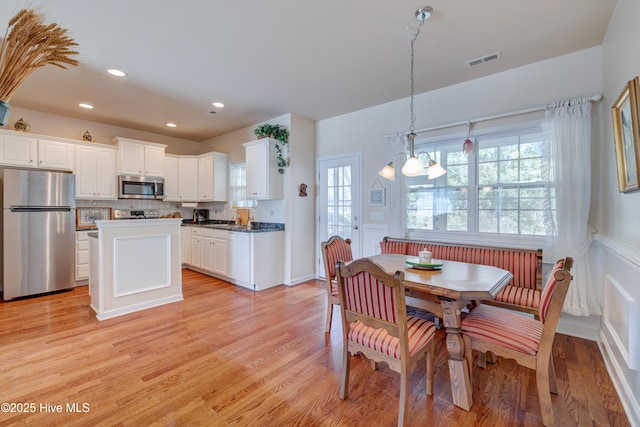 dining area with light wood-type flooring and an inviting chandelier