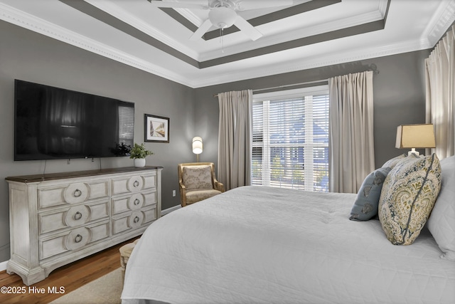 bedroom with hardwood / wood-style floors, a raised ceiling, ceiling fan, and ornamental molding