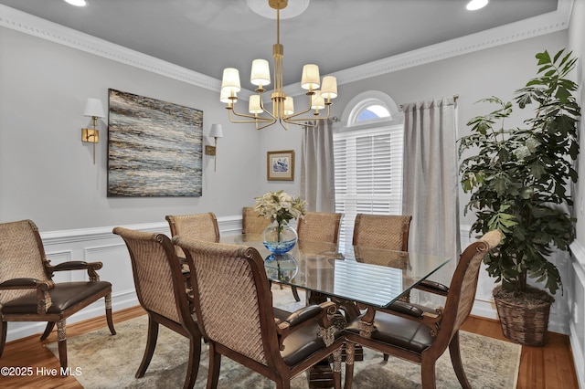 dining area with hardwood / wood-style flooring, an inviting chandelier, and crown molding