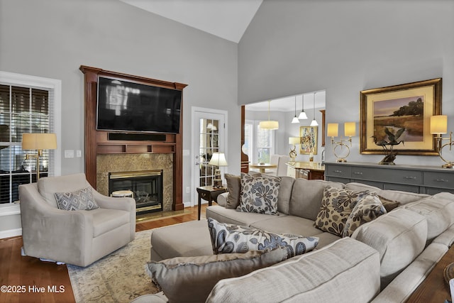 living room featuring high vaulted ceiling, a wealth of natural light, wood-type flooring, and a high end fireplace