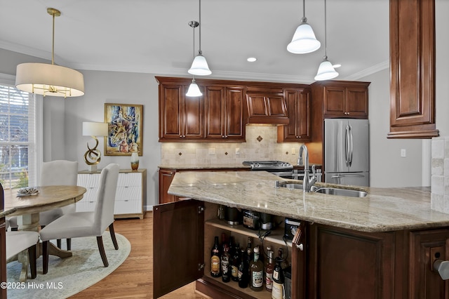 kitchen with light stone counters, ornamental molding, hanging light fixtures, and appliances with stainless steel finishes