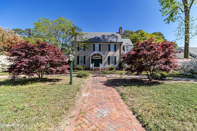 view of front of property featuring a chimney and a front yard