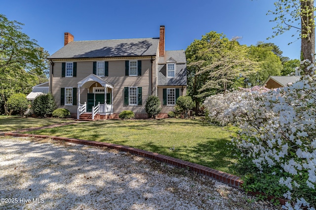 colonial inspired home featuring a chimney and a front lawn