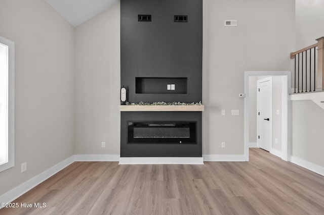 unfurnished living room with light wood-type flooring and vaulted ceiling