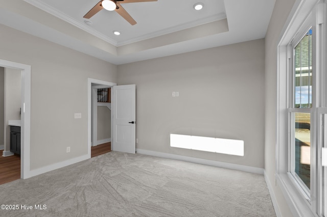 unfurnished bedroom with a raised ceiling, light carpet, crown molding, and ceiling fan