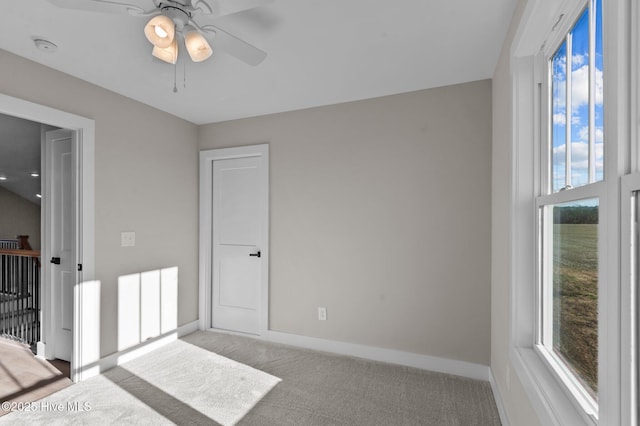 unfurnished bedroom featuring multiple windows, ceiling fan, and light carpet