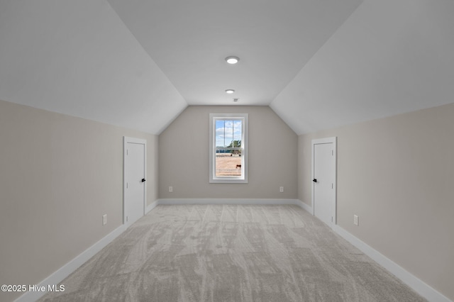 additional living space with light colored carpet and vaulted ceiling