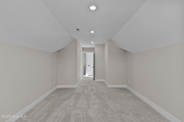 bonus room with light colored carpet and vaulted ceiling