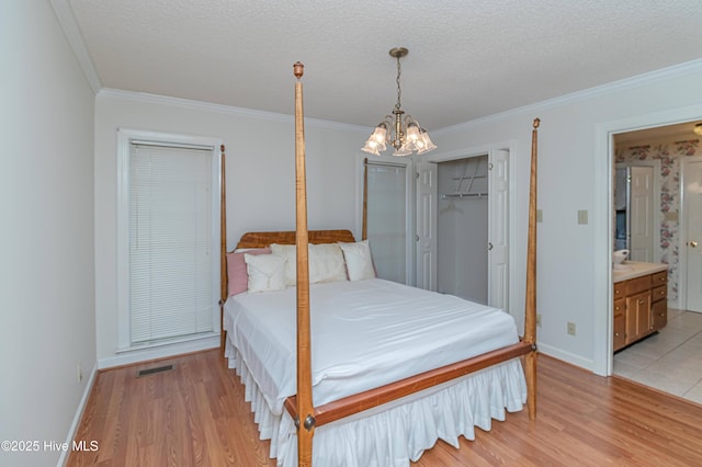 bedroom featuring crown molding, a notable chandelier, a textured ceiling, and light hardwood / wood-style flooring