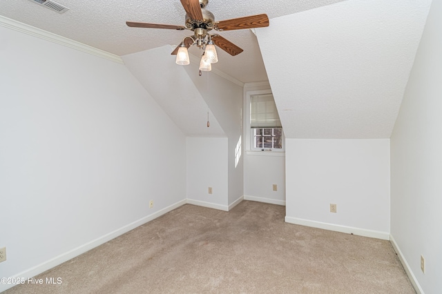 additional living space with ceiling fan, vaulted ceiling, light carpet, and a textured ceiling