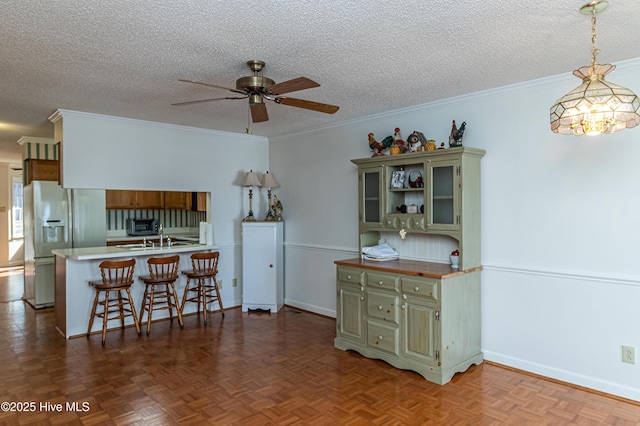 kitchen with refrigerator with ice dispenser, a breakfast bar area, ceiling fan, green cabinetry, and kitchen peninsula