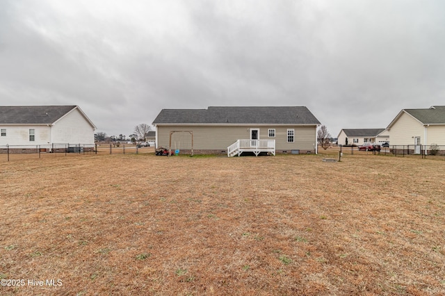 rear view of property featuring a wooden deck and a lawn