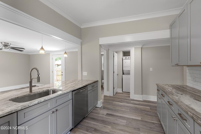 kitchen featuring gray cabinetry, ceiling fan, sink, stainless steel dishwasher, and stacked washer and clothes dryer