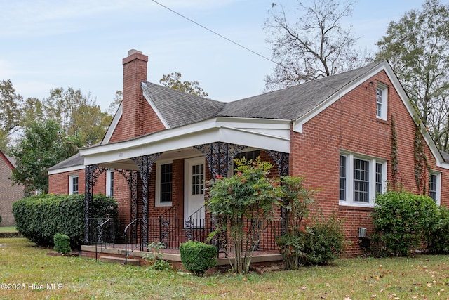 exterior space with a porch, a front yard, brick siding, and a chimney