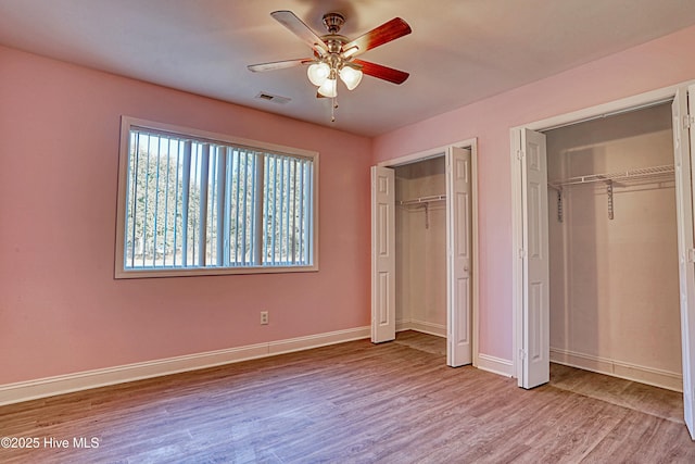 unfurnished bedroom with ceiling fan, light wood-type flooring, and multiple closets