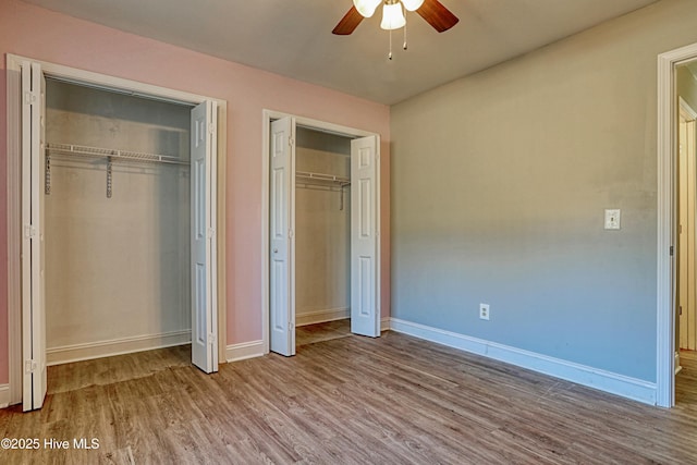 unfurnished bedroom with light hardwood / wood-style floors, ceiling fan, and two closets