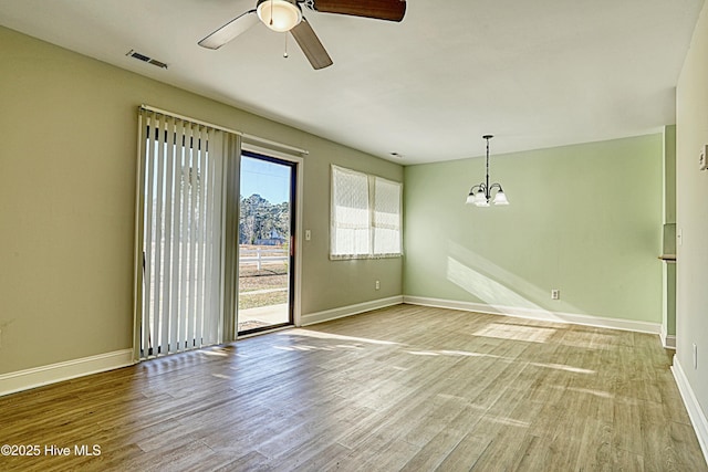 unfurnished room featuring ceiling fan with notable chandelier and light hardwood / wood-style floors