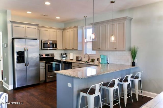 kitchen with decorative light fixtures, light stone countertops, kitchen peninsula, and stainless steel appliances