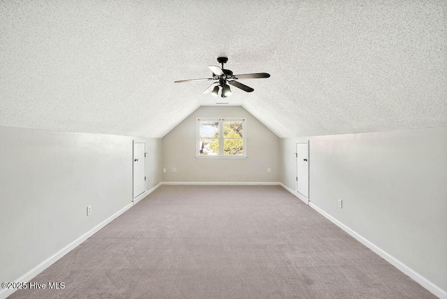 additional living space with a textured ceiling, ceiling fan, light colored carpet, and vaulted ceiling