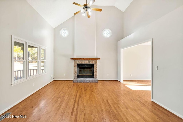 unfurnished living room featuring ceiling fan, a fireplace, high vaulted ceiling, and light hardwood / wood-style flooring