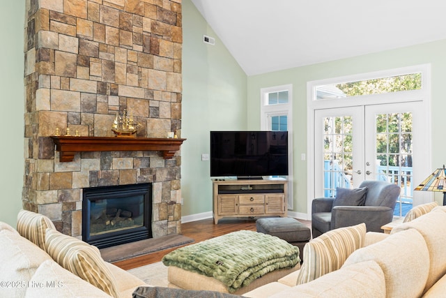 4379 Gauntlet Dr, Southport, NC 28461 - living room with high vaulted ceiling, wood finished floors, french doors, a stone fireplace, and baseboards