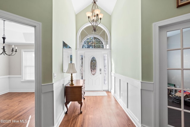 4379 Gauntlet Dr, Southport, NC 28461 - entrance foyer featuring a chandelier, hardwood / wood-style flooring, plenty of natural light, a wainscoted wall, and high vaulted ceiling