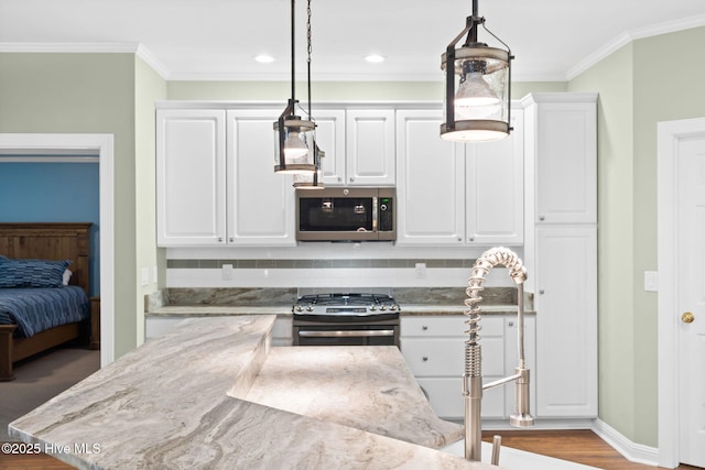 4379 Gauntlet Dr, Southport, NC 28461 - kitchen with stainless steel appliances, white cabinets, hanging light fixtures, ornamental molding, and wood finished floors
