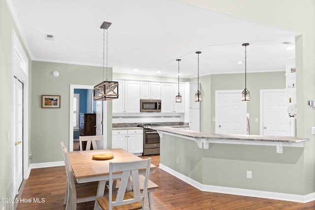 4379 Gauntlet Dr, Southport, NC 28461 - kitchen featuring stainless steel appliances, crown molding, a kitchen bar, white cabinetry, and baseboards