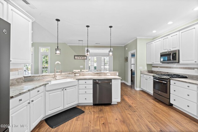 kitchen with white cabinetry, crown molding, pendant lighting, a breakfast bar area, and appliances with stainless steel finishes