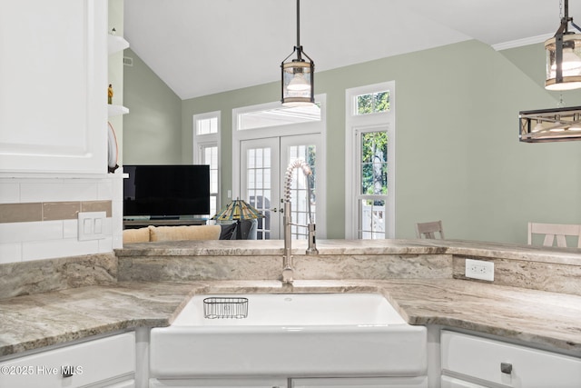 4379 Gauntlet Dr, Southport, NC 28461 - kitchen with a sink, healthy amount of natural light, white cabinets, vaulted ceiling, and decorative light fixtures