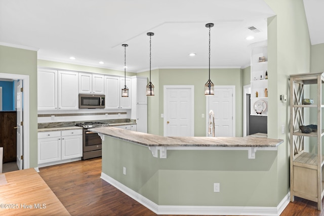 4379 Gauntlet Dr, Southport, NC 28461 - kitchen with appliances with stainless steel finishes, white cabinets, a breakfast bar area, dark wood-type flooring, and crown molding