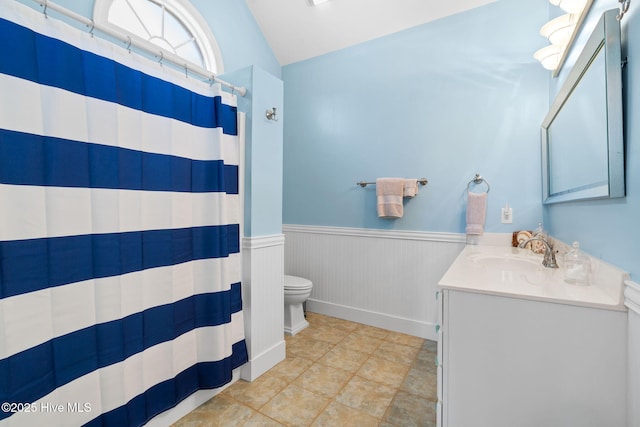 4379 Gauntlet Dr, Southport, NC 28461 - bathroom featuring toilet, vanity, a wainscoted wall, a shower with curtain, and vaulted ceiling