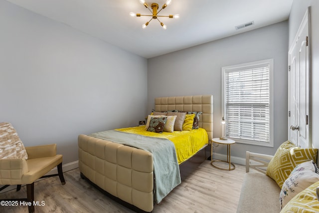 bedroom with hardwood / wood-style floors and a notable chandelier