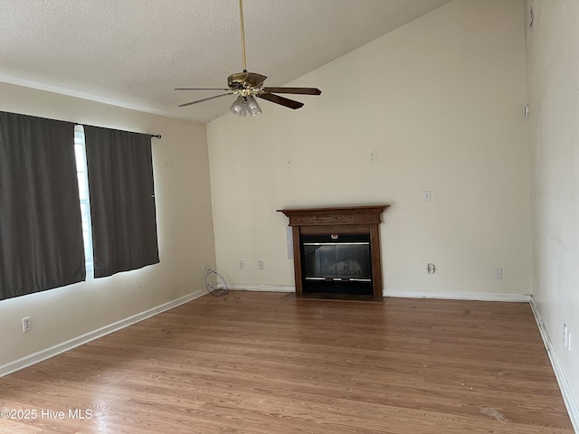 unfurnished living room featuring hardwood / wood-style flooring, ceiling fan, vaulted ceiling, and a textured ceiling