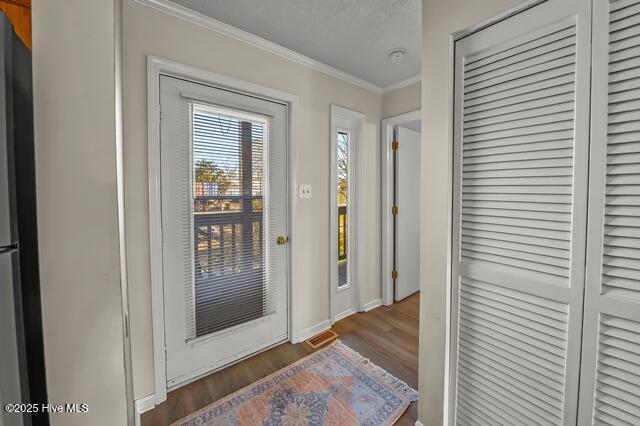 doorway to outside featuring crown molding and dark hardwood / wood-style flooring