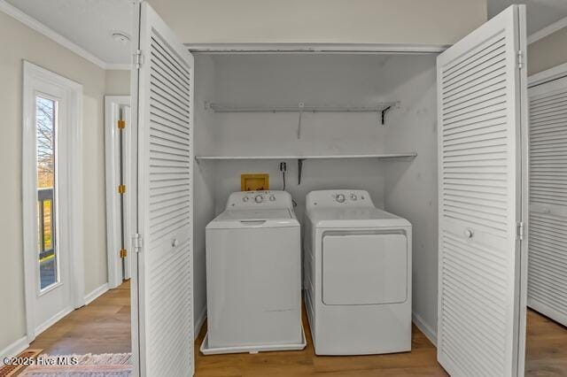 clothes washing area with separate washer and dryer, wood-type flooring, and ornamental molding