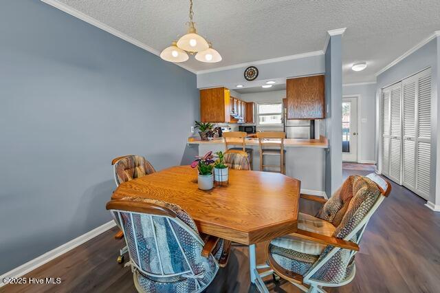 dining room featuring a textured ceiling, crown molding, and dark wood-type flooring