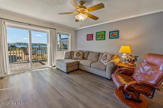 living room with ceiling fan, crown molding, a textured ceiling, a water view, and hardwood / wood-style flooring