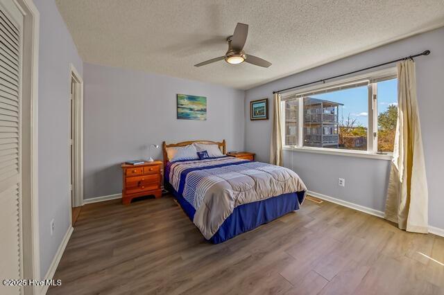 bedroom with hardwood / wood-style floors, ceiling fan, a textured ceiling, and a closet