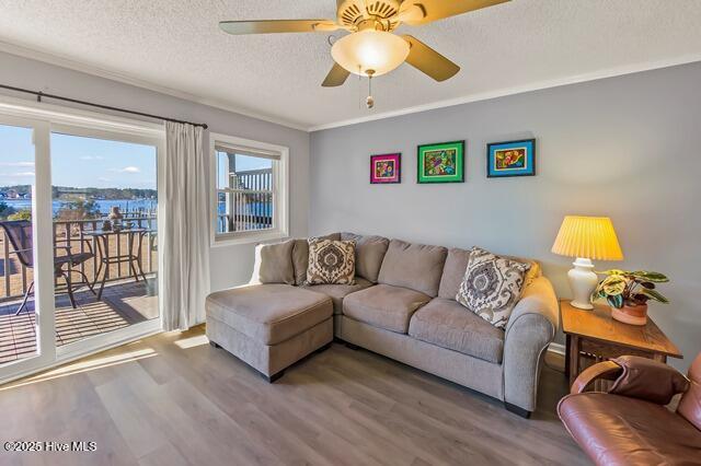 living room with hardwood / wood-style flooring, ceiling fan, ornamental molding, and a textured ceiling