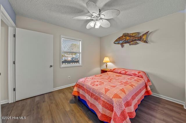 bedroom with dark hardwood / wood-style flooring, a textured ceiling, and ceiling fan